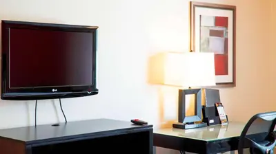 a flat screen tv sitting on a table with a lamp at Studio 6 Anaheim Hills CA in Anaheim