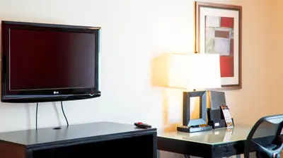 a flat screen tv sitting on a desk with a lamp at Studio 6 Anaheim Hills CA in Anaheim