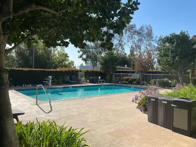 a swimming pool in a yard with a tree at SureStay Hotel by Best Western Ontario Airport in Ontario