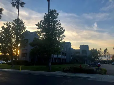 a large white building with a palm tree and a street at SureStay Hotel by Best Western Ontario Airport in Ontario