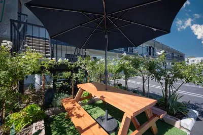 a wooden picnic table with an umbrella in front of a building at Unik Motel in Harbor City