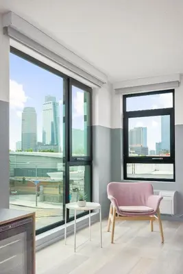 a living room with a pink chair and a large window at The Metric - Los Angeles Downtown in Los Angeles