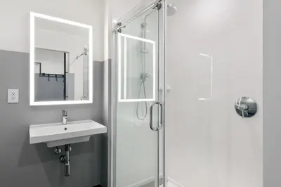 a white bathroom with a sink and a shower at The Metric - Los Angeles Downtown in Los Angeles