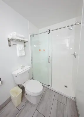 a bathroom with a toilet and a glass shower at Travelodge Inn & Suites by Wyndham West Covina in West Covina