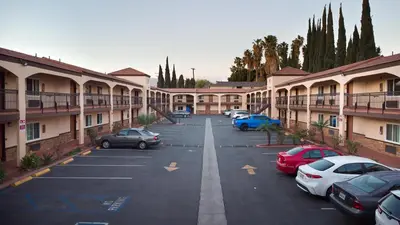 a parking lot with cars parked in front of buildings at Travelodge Inn & Suites by Wyndham West Covina in West Covina