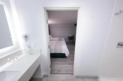 a bathroom with a sink and a bed in a room at Travelodge Inn & Suites by Wyndham West Covina in West Covina