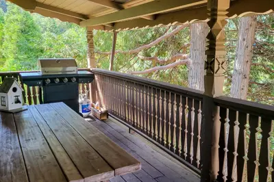 a porch with a wooden bench and a grill at Alpine Dream in Crestline