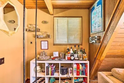 a room with a book shelf with bottles on it at Running Springs A-Frame with Deck and Mtn Views! in Running Springs