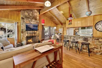a living room with a fireplace and a stone wall at Marin Getaway #2013 by Big Bear Vacations in Big Bear Lake