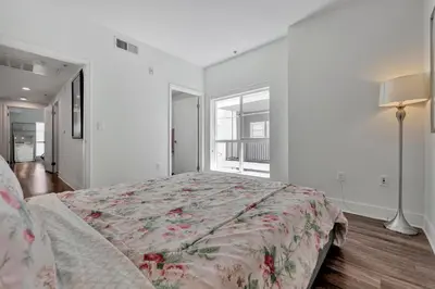 a white bedroom with a bed with a floral bedspread at 7 Large Down Town Santa Monica Apartment in Los Angeles