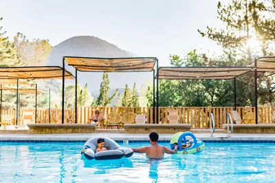 two children in an outdoor swimming pool with inflatables at Huttopia Paradise Springs in Valyermo