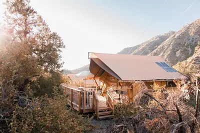 a cabin in the mountains with mountains in the background at Huttopia Paradise Springs in Valyermo