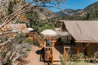 a resort with a deck with an umbrella at Huttopia Paradise Springs in Valyermo