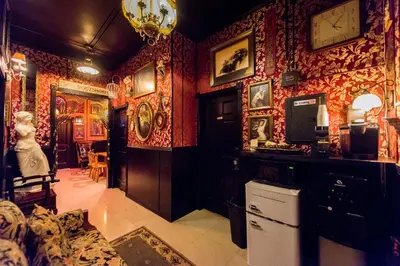 a living room with red wallpaper and a woman standing in it at The Rosemary in Los Angeles