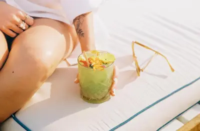 a woman sitting on a bed holding a drink at SIXTY Beverly Hills in Los Angeles
