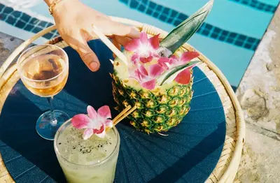 a person holding a pineapple with a drink on a table at SIXTY Beverly Hills in Los Angeles