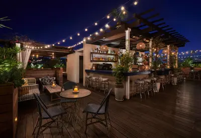 a bar with chairs and tables on a deck at night at SIXTY Beverly Hills in Los Angeles