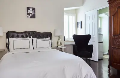 a bedroom with a white bed and a black chair at Hollywood Hills Homestay in Los Angeles