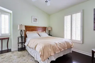 a bedroom with a bed with white walls and windows at Hollywood Hills Homestay in Los Angeles