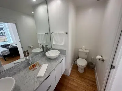 a white bathroom with two sinks and a toilet at One Lux Stay HWH Downtown Los Angeles in Los Angeles