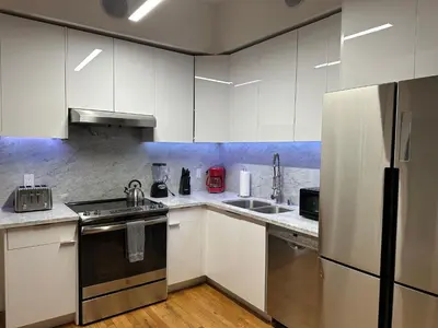 a kitchen with white cabinets and a stainless steel refrigerator at One Lux Stay HWH Downtown Los Angeles in Los Angeles