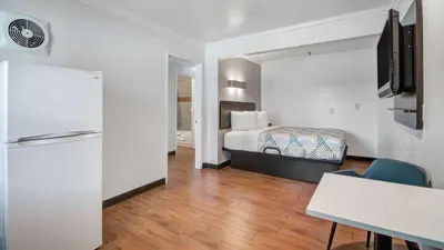 a hotel room with a bed and a refrigerator at Studio 6 Ontario CA Convention Center Airport in Ontario