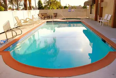 a swimming pool with blue water and chairs and tables at Abby's Anaheimer Inn - Across Disneyland Park in Anaheim