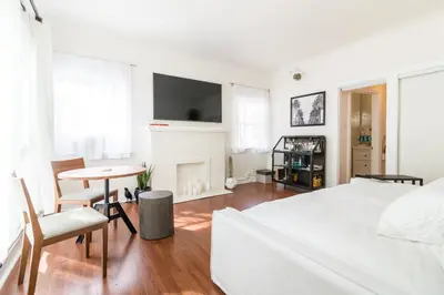 a bedroom with a bed and a table and a fireplace at Sunny Boho Chic West Hollywood Flat! in Los Angeles