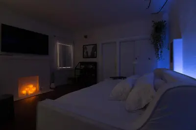 a bedroom with a white bed in a dark room at Sunny Boho Chic West Hollywood Flat! in Los Angeles