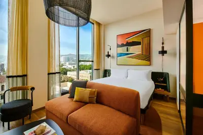 a hotel room with a bed and a couch and a window at HOLLYWOOD VOLUME, a Tribute Portfolio Hotel in Los Angeles