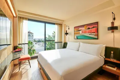 a bedroom with a large bed and a large window at HOLLYWOOD VOLUME, a Tribute Portfolio Hotel in Los Angeles