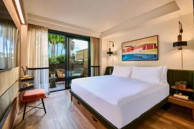 a bedroom with a large white bed and a balcony at HOLLYWOOD VOLUME, a Tribute Portfolio Hotel in Los Angeles