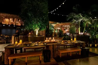 a restaurant with tables and chairs with candles and plants at HOLLYWOOD VOLUME, a Tribute Portfolio Hotel in Los Angeles