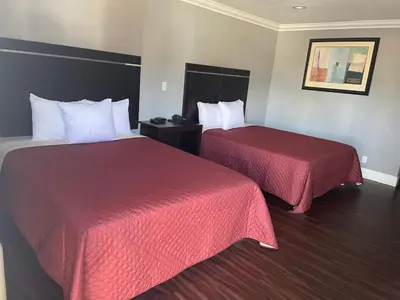 two beds in a hotel room with red sheets at Legacy inn & suites in Anaheim