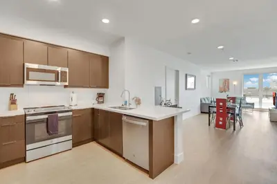 a kitchen with wooden cabinets and a living room at Apart Hotel near Dodgers Stadium in Los Angeles