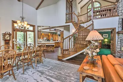 a living room with a staircase and a table and chairs at Ornate Lake Arrowhead Home with Deck in Lake Arrowhead