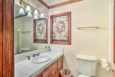 a bathroom with a sink and a toilet and a mirror at Ornate Lake Arrowhead Home with Deck in Lake Arrowhead