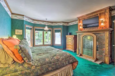 a bedroom with a bed and a fireplace and a tv at Ornate Lake Arrowhead Home with Deck in Lake Arrowhead