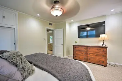 a bedroom with a bed and a tv and a dresser at Bakersfield Oasis Sweet Tropical Pool Setup! in Bakersfield