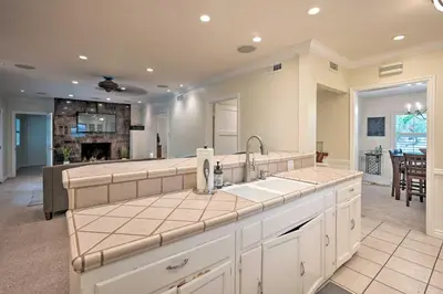 a kitchen with a sink and a living room at Bakersfield Oasis Sweet Tropical Pool Setup! in Bakersfield