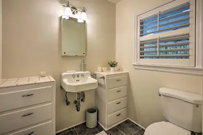 a bathroom with a sink and a toilet and a mirror at Bakersfield Oasis Sweet Tropical Pool Setup! in Bakersfield