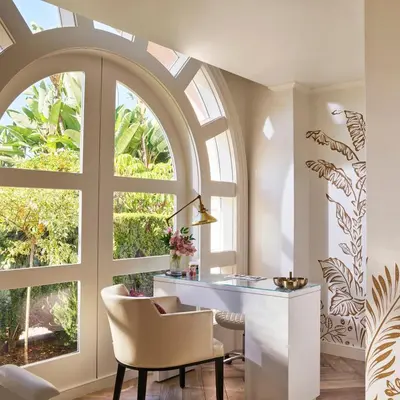 an arched window in a room with a desk and a chair at The Beverly Hills Hotel - Dorchester Collection in Los Angeles