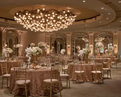 a ballroom with tables and chairs and a chandelier at The Beverly Hills Hotel - Dorchester Collection in Los Angeles
