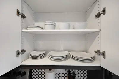 a kitchen with white plates and bowls on shelves at Apart Hotel at Chinatown in Los Angeles