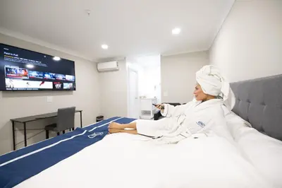 a woman sitting on a bed in a room at Omeo Suites in Alhambra