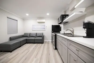 a living room with a couch and a kitchen at Omeo Suites in Alhambra