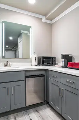 a kitchen with gray cabinets and a mirror at Omeo Suites in Alhambra