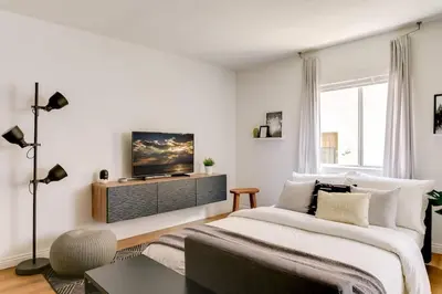 a white bedroom with a large bed and a tv at Sophisticated Long Beach Suite with Patio Dining and Parking NRP21-00185 in Long Beach