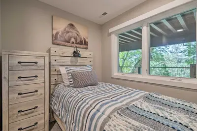 a bedroom with a bed and a dresser and two windows at Airy Alpine Getaway with Lake Arrowhead Views! in Lake Arrowhead