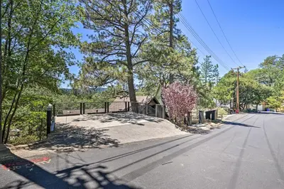 an empty street with a fence and a tree at Airy Alpine Getaway with Lake Arrowhead Views! in Lake Arrowhead